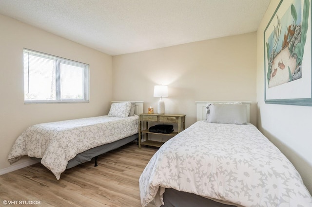 bedroom with a textured ceiling and light hardwood / wood-style flooring