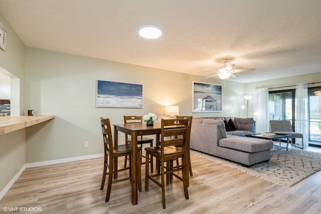 dining space with ceiling fan, light hardwood / wood-style floors, and a textured ceiling