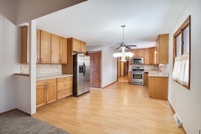 kitchen featuring appliances with stainless steel finishes, sink, backsplash, light wood-type flooring, and ceiling fan