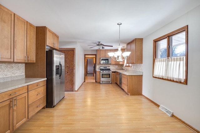 kitchen with pendant lighting, stainless steel appliances, decorative backsplash, sink, and light hardwood / wood-style flooring