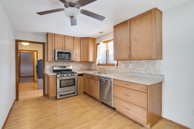 kitchen featuring light wood-type flooring, stainless steel appliances, backsplash, and sink