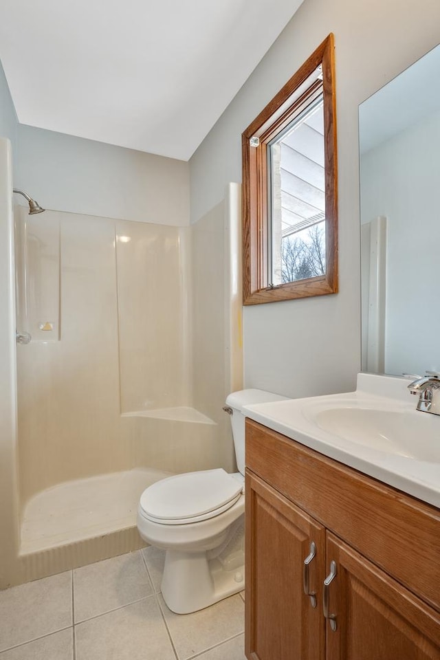 bathroom featuring tile patterned flooring, toilet, walk in shower, and vanity