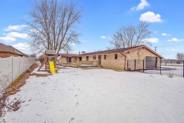 snow covered back of property featuring a playground