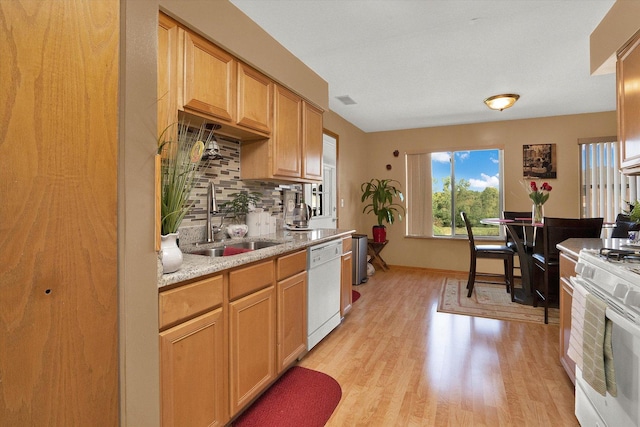 kitchen featuring sink, light stone counters, backsplash, light hardwood / wood-style floors, and white appliances