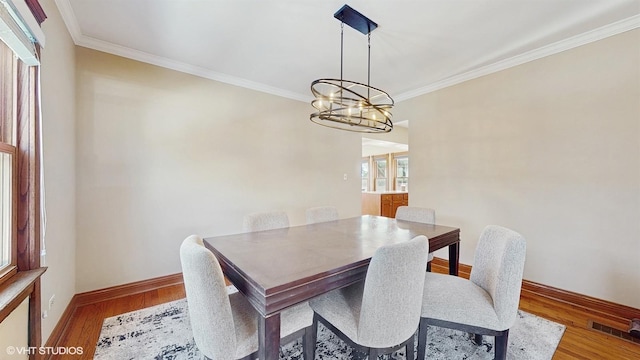 dining space with a healthy amount of sunlight, crown molding, a chandelier, and wood-type flooring