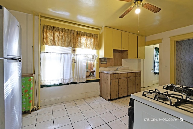 kitchen with gas range gas stove, ceiling fan, sink, stainless steel refrigerator, and light tile patterned flooring