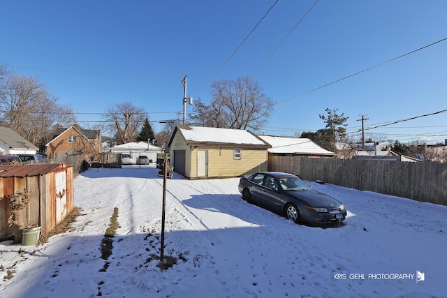 yard covered in snow featuring an outbuilding and a garage