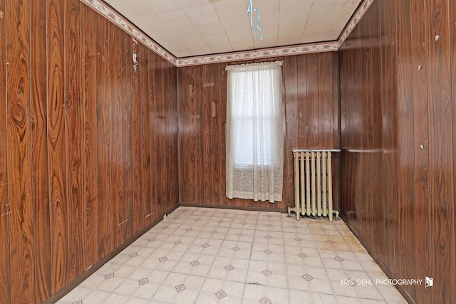 spare room with plenty of natural light, wood walls, and radiator heating unit