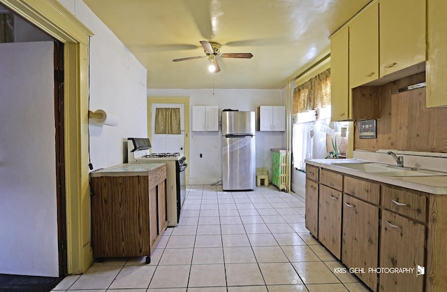 kitchen with stainless steel refrigerator, ceiling fan, sink, light tile patterned floors, and white stove