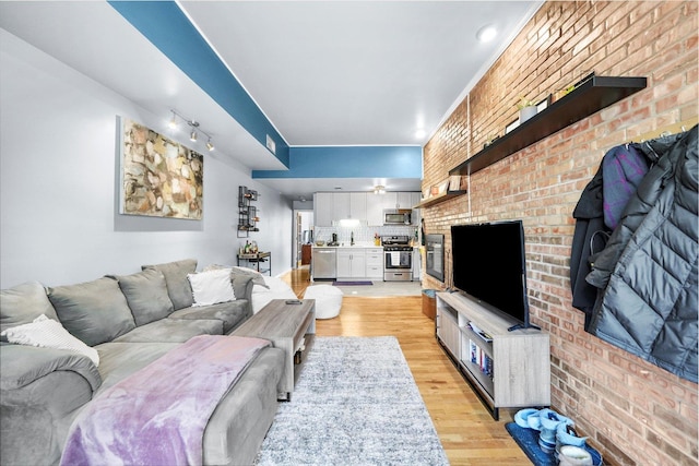 living room featuring brick wall and light wood-type flooring