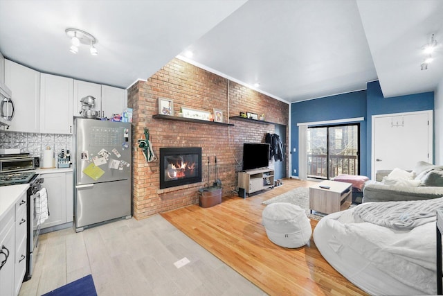 living room with brick wall, a brick fireplace, and light hardwood / wood-style floors