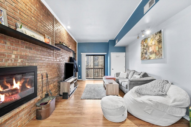 living room featuring brick wall, a brick fireplace, and light hardwood / wood-style flooring