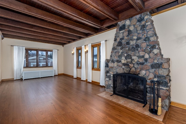 unfurnished living room with a fireplace, beamed ceiling, wood-type flooring, radiator heating unit, and wood ceiling