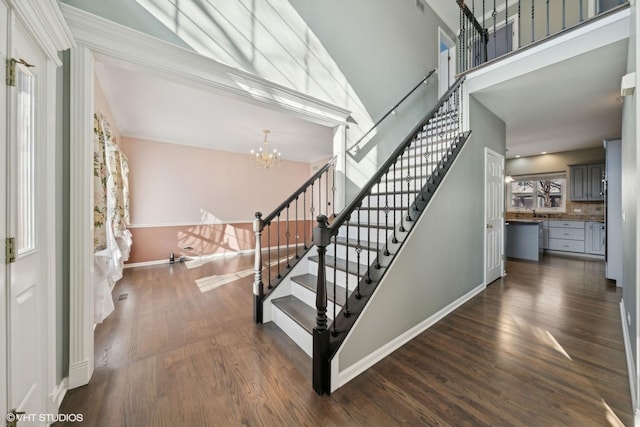 staircase with a high ceiling, a notable chandelier, and hardwood / wood-style floors