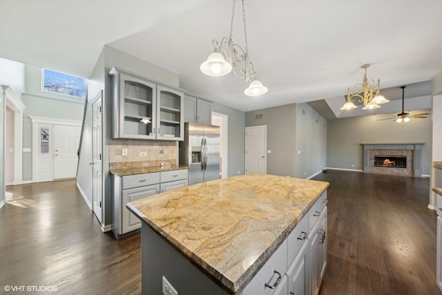 kitchen featuring gray cabinetry, a center island, stainless steel fridge with ice dispenser, light stone counters, and backsplash