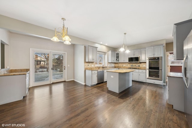 kitchen with pendant lighting, a kitchen island, appliances with stainless steel finishes, and tasteful backsplash