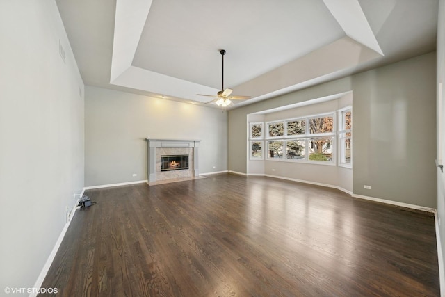 unfurnished living room featuring ceiling fan, dark hardwood / wood-style flooring, a fireplace, and a tray ceiling