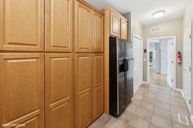 kitchen featuring black fridge, light brown cabinets, and light tile patterned flooring