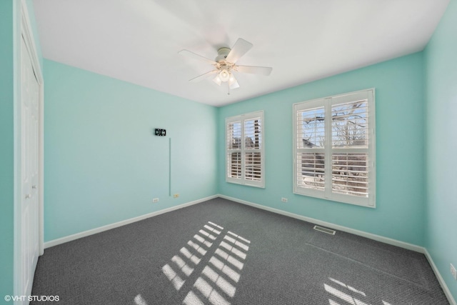 spare room featuring dark carpet and ceiling fan