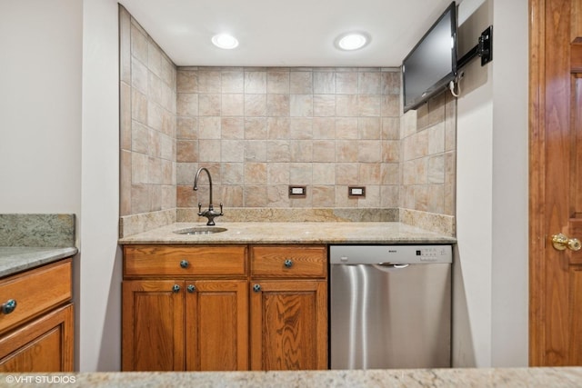 kitchen with light stone countertops, stainless steel dishwasher, and sink