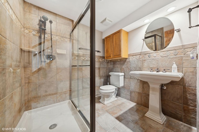 bathroom featuring a shower with shower door, tile walls, and toilet