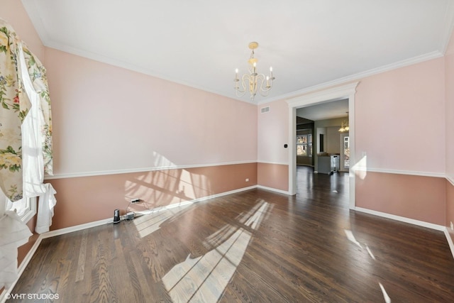 spare room featuring a wealth of natural light, ornamental molding, dark wood-type flooring, and an inviting chandelier