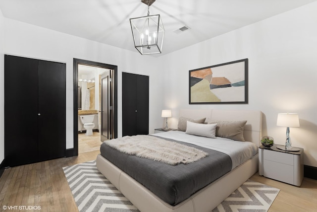 bedroom featuring ensuite bath, light hardwood / wood-style floors, and a notable chandelier