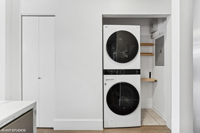 clothes washing area with stacked washer / dryer and electric panel