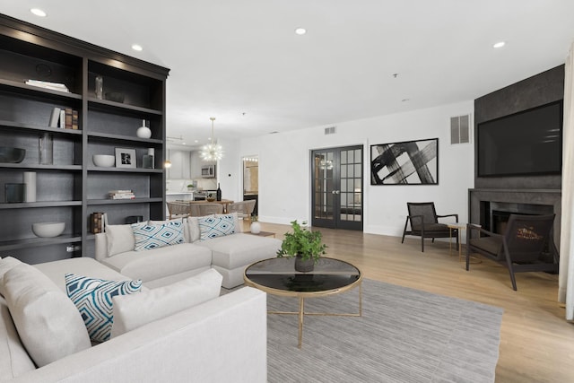 living room featuring french doors, a fireplace, and light hardwood / wood-style floors