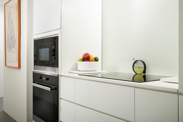 kitchen featuring white cabinetry, black oven, and built in microwave