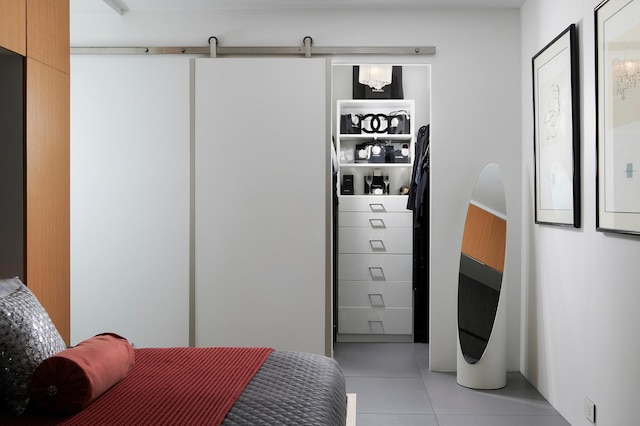 bedroom with a barn door and light tile patterned flooring