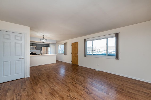 unfurnished living room with dark hardwood / wood-style flooring and a chandelier