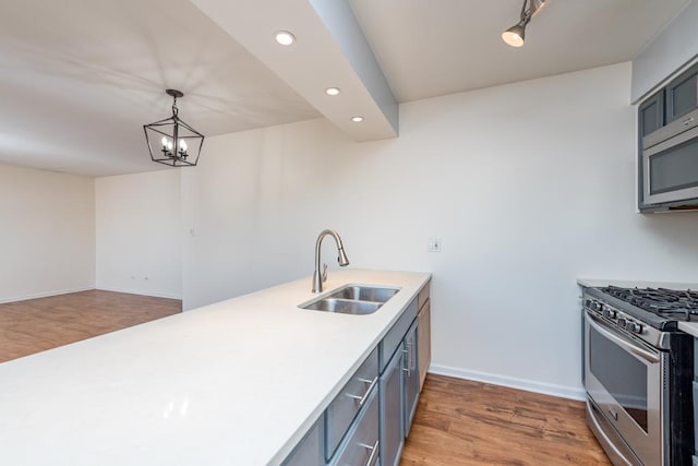 kitchen featuring sink, hanging light fixtures, gray cabinets, stainless steel appliances, and hardwood / wood-style floors