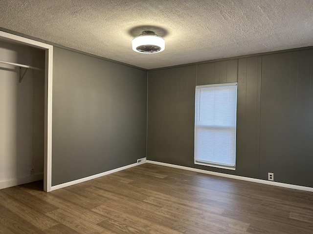 unfurnished bedroom with a closet, a textured ceiling, and dark wood-type flooring