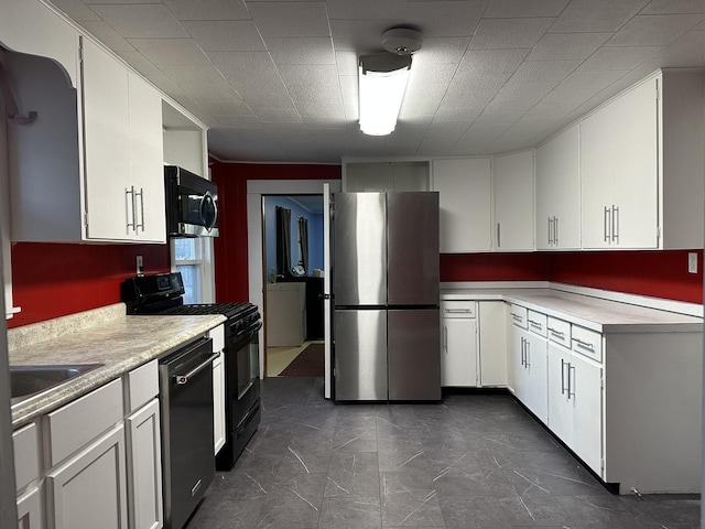 kitchen with appliances with stainless steel finishes, white cabinets, washer / dryer, and sink