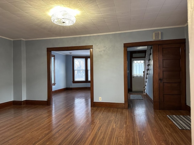 spare room with a chandelier, ornamental molding, and dark hardwood / wood-style floors