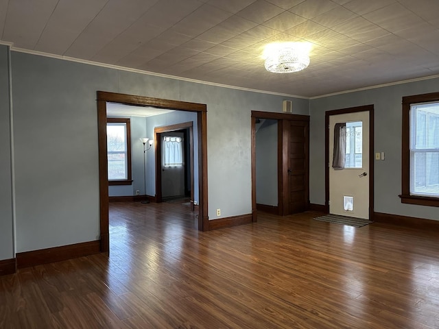 spare room with dark hardwood / wood-style flooring, an inviting chandelier, and crown molding