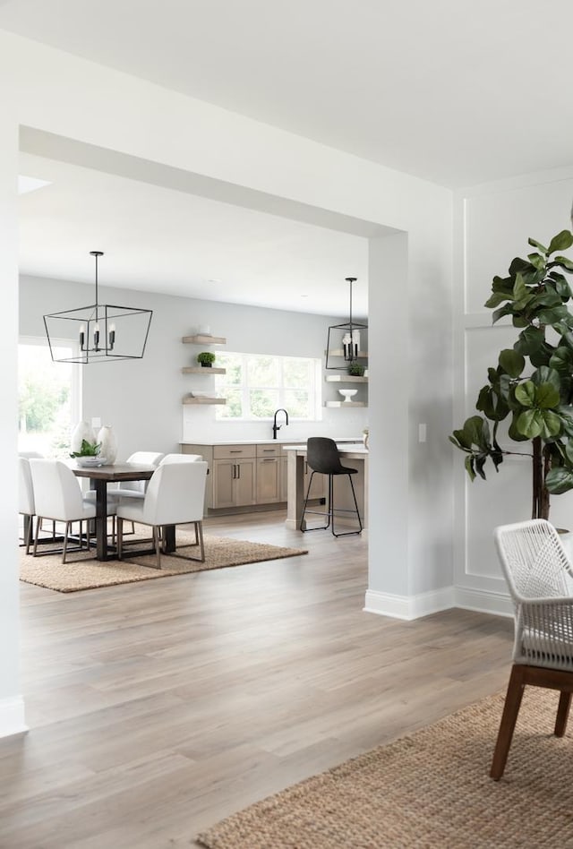 dining area featuring light hardwood / wood-style floors, sink, and a notable chandelier