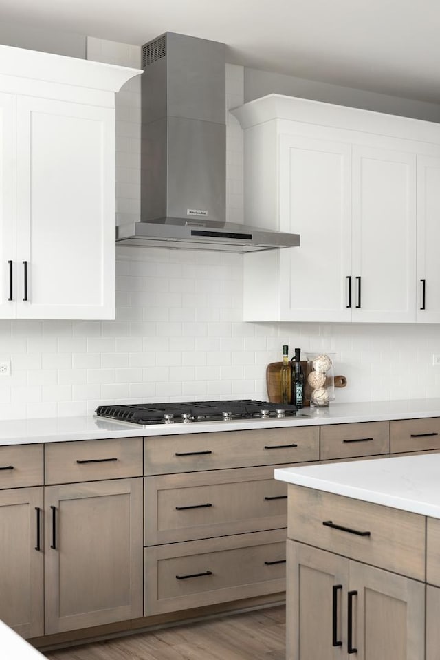 kitchen featuring light hardwood / wood-style floors, backsplash, wall chimney exhaust hood, and stainless steel gas cooktop