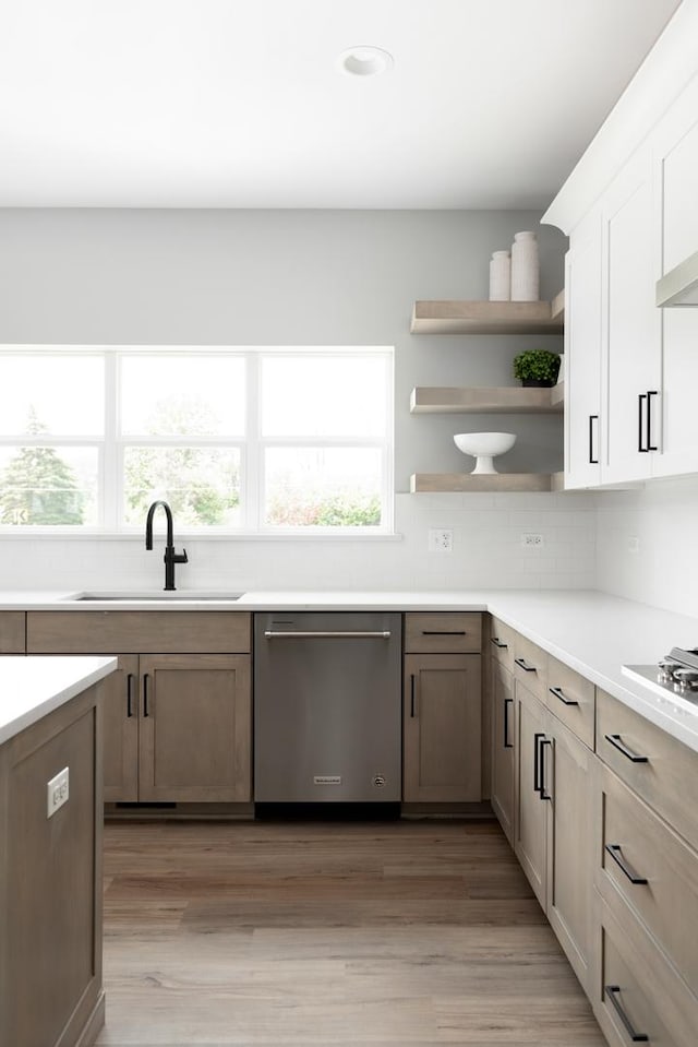 kitchen with sink, white cabinetry, dishwasher, and light hardwood / wood-style flooring