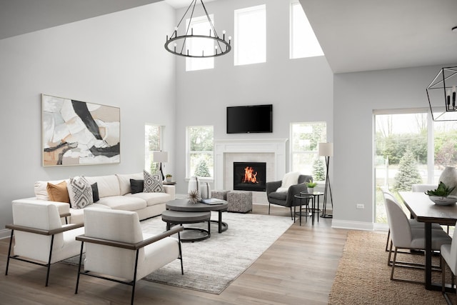 living room with light wood-type flooring, a high ceiling, and an inviting chandelier