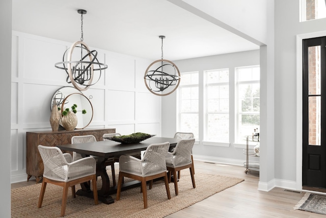 dining space with light hardwood / wood-style flooring and an inviting chandelier