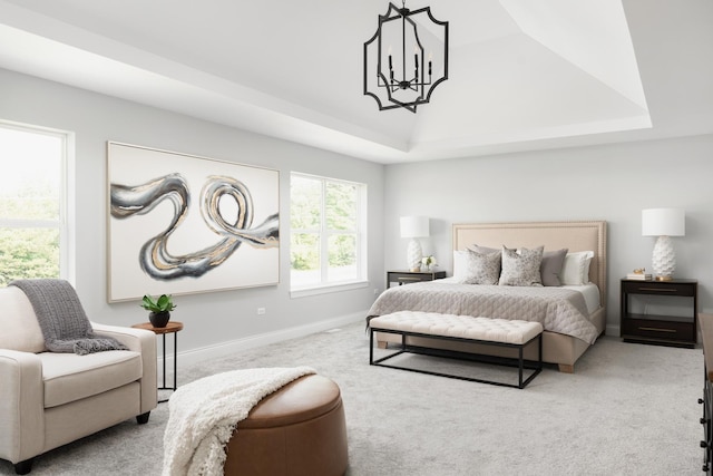 carpeted bedroom with a raised ceiling and an inviting chandelier