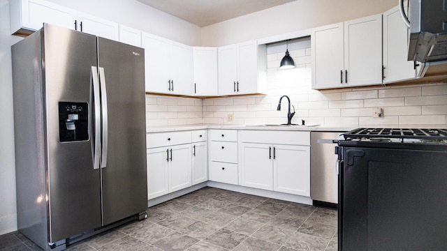 kitchen featuring pendant lighting, appliances with stainless steel finishes, white cabinetry, tasteful backsplash, and sink