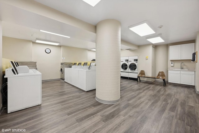 laundry room with washing machine and dryer, wood-type flooring, and sink