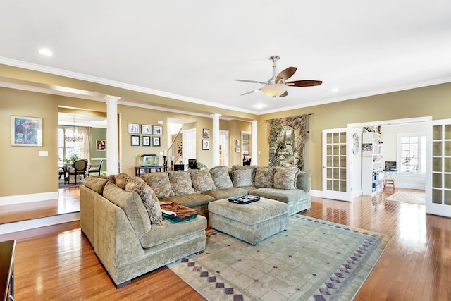 living room with crown molding, plenty of natural light, ornate columns, and light wood-type flooring