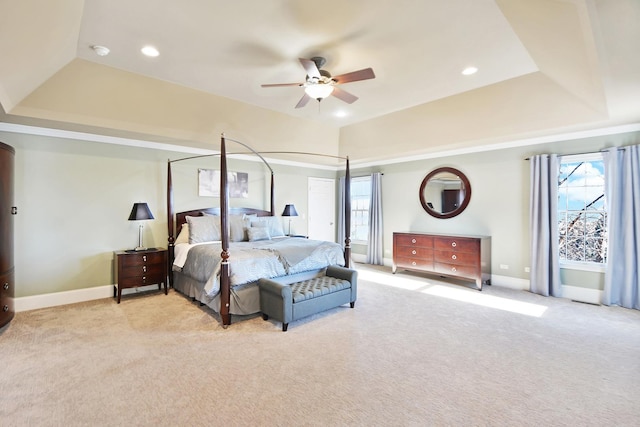 bedroom featuring light colored carpet, a raised ceiling, and ceiling fan