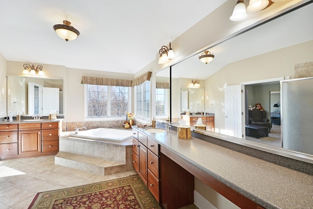 bathroom featuring vanity, vaulted ceiling, tiled bath, and tile patterned floors