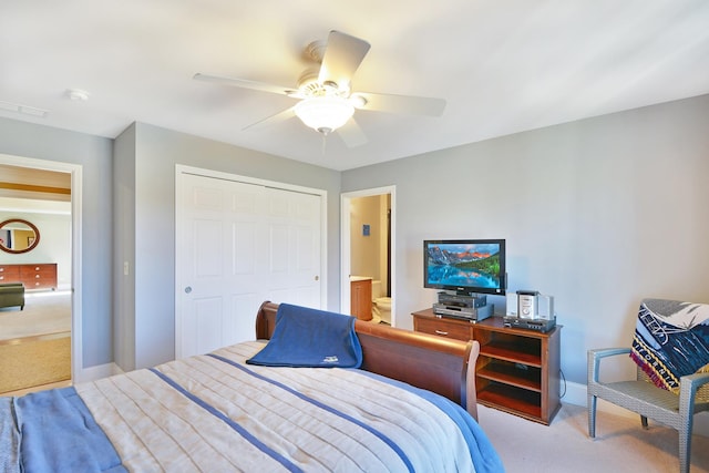 carpeted bedroom featuring ensuite bath, ceiling fan, and a closet