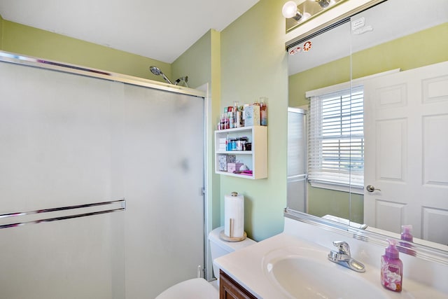 bathroom featuring vanity, toilet, and a shower with door